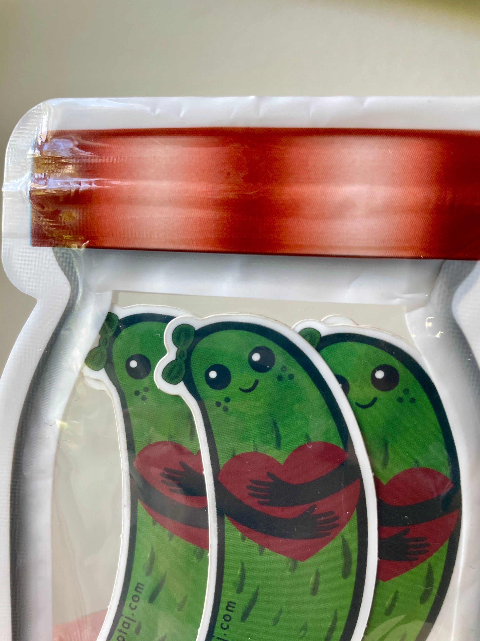 Plastic bag that looks like a jar filled with stickers that look like adorable happy pickles holding a heart.